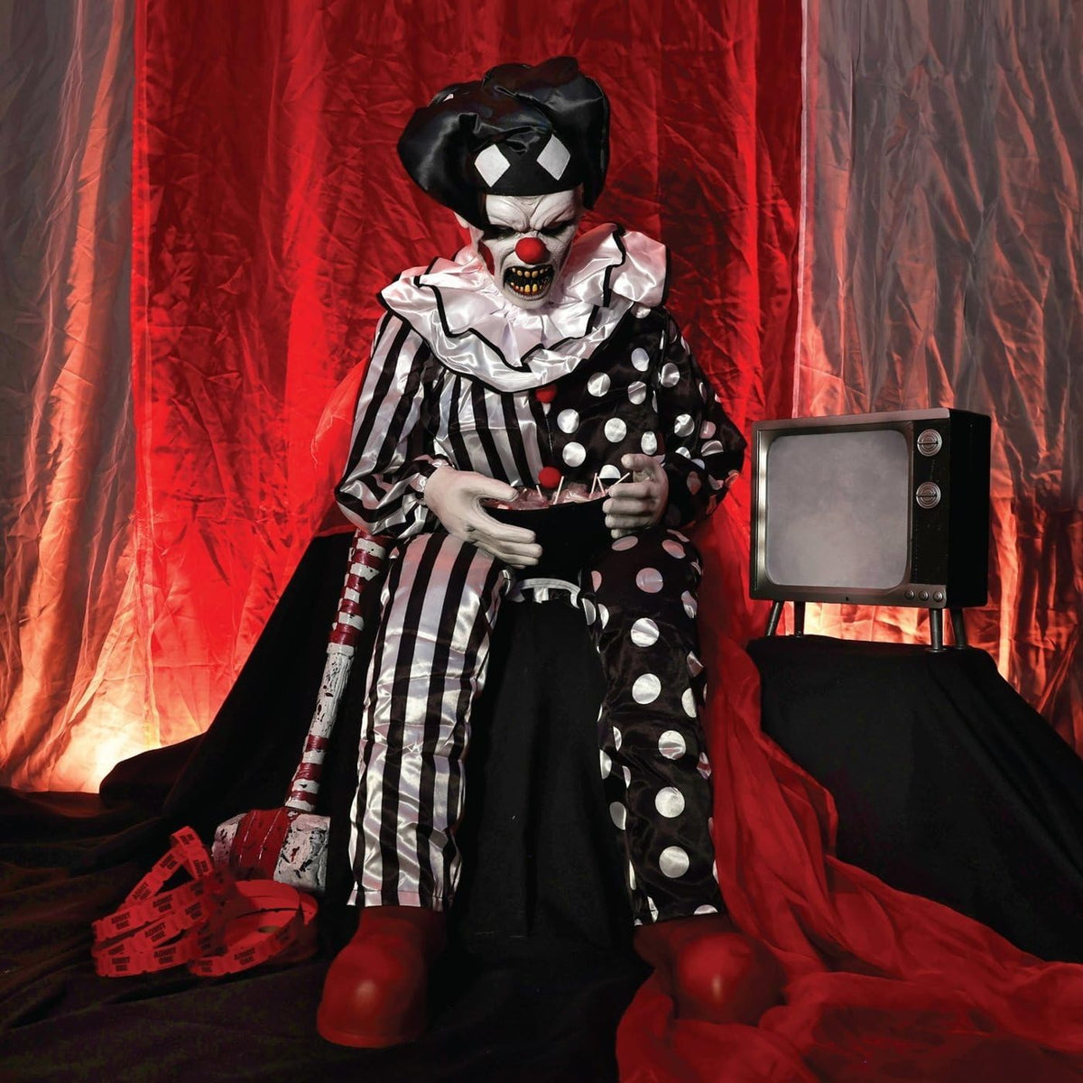 Clown seated in front of red stage curtains